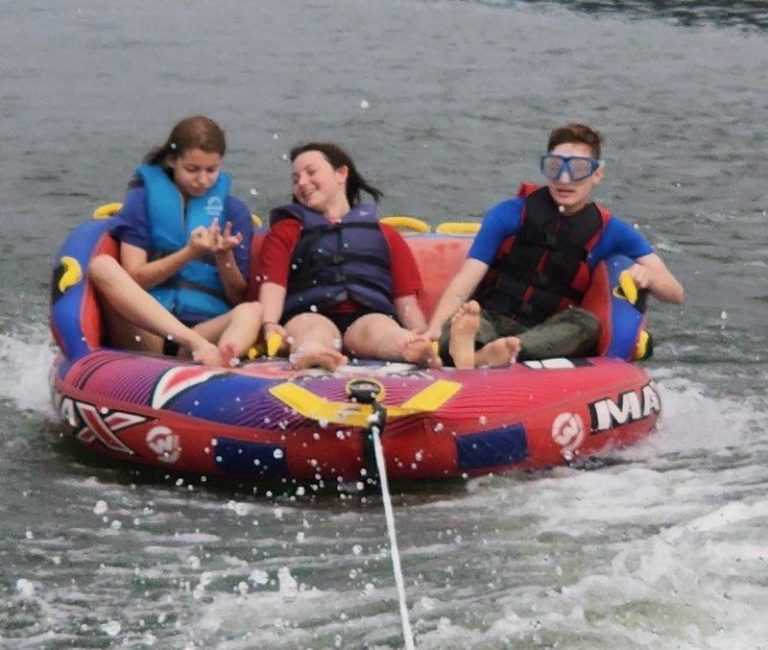 Three scouts riding a towed tube across a lake