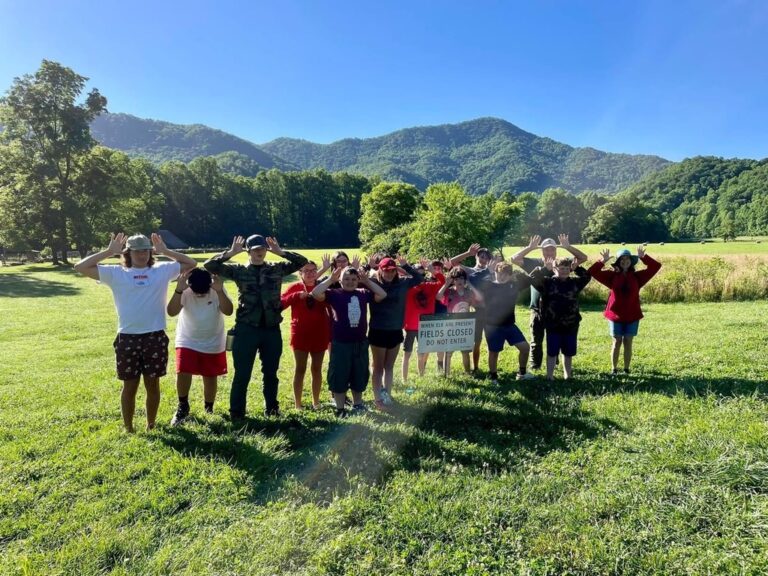 Scouts posing in a meadow with mountains behind them